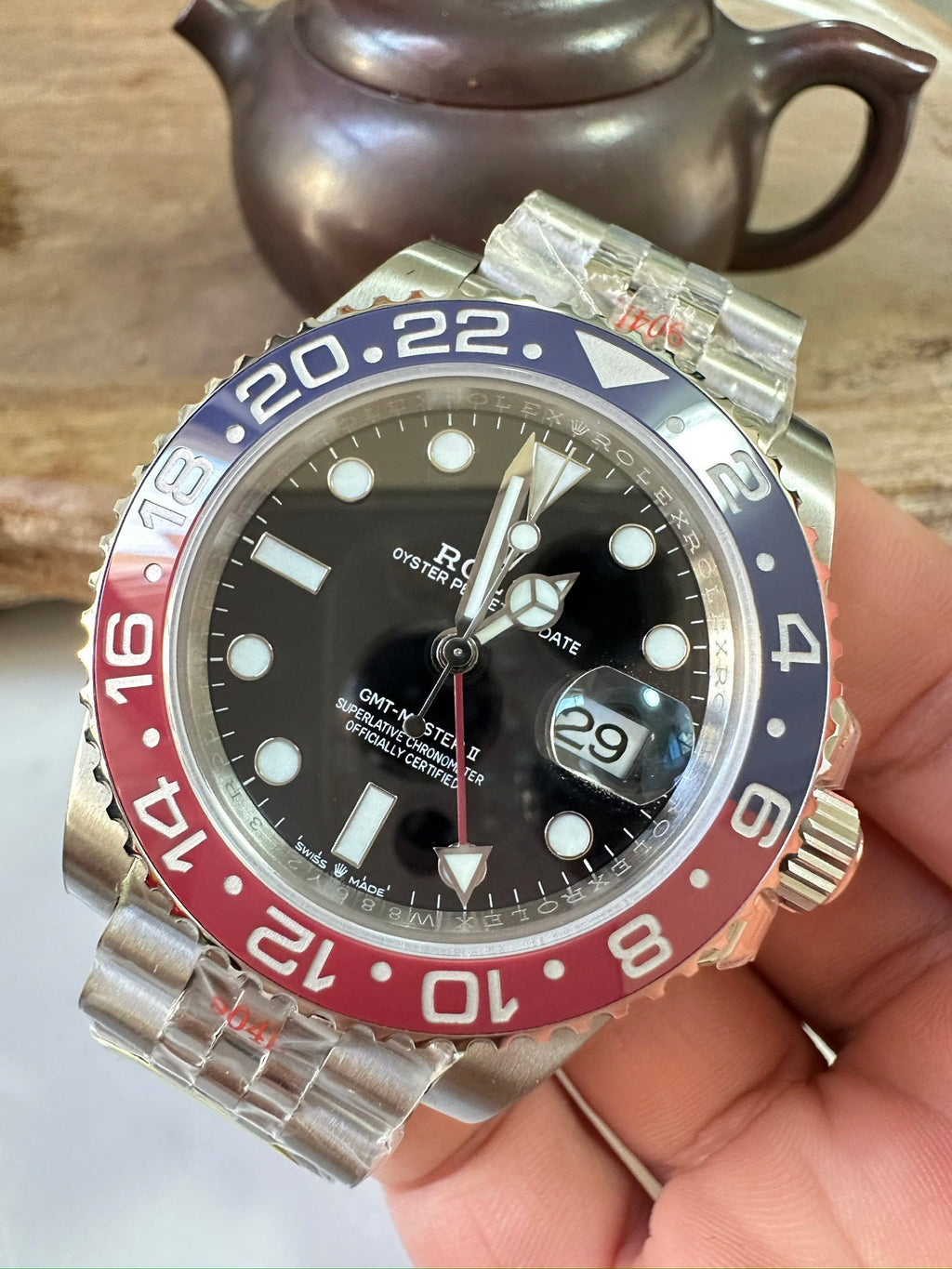 Rolex GMT watch front with black dial, blue/red bezel, metal bracelet and date