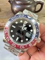 Rolex GMT watch front with black dial, blue/red bezel, metal bracelet and date