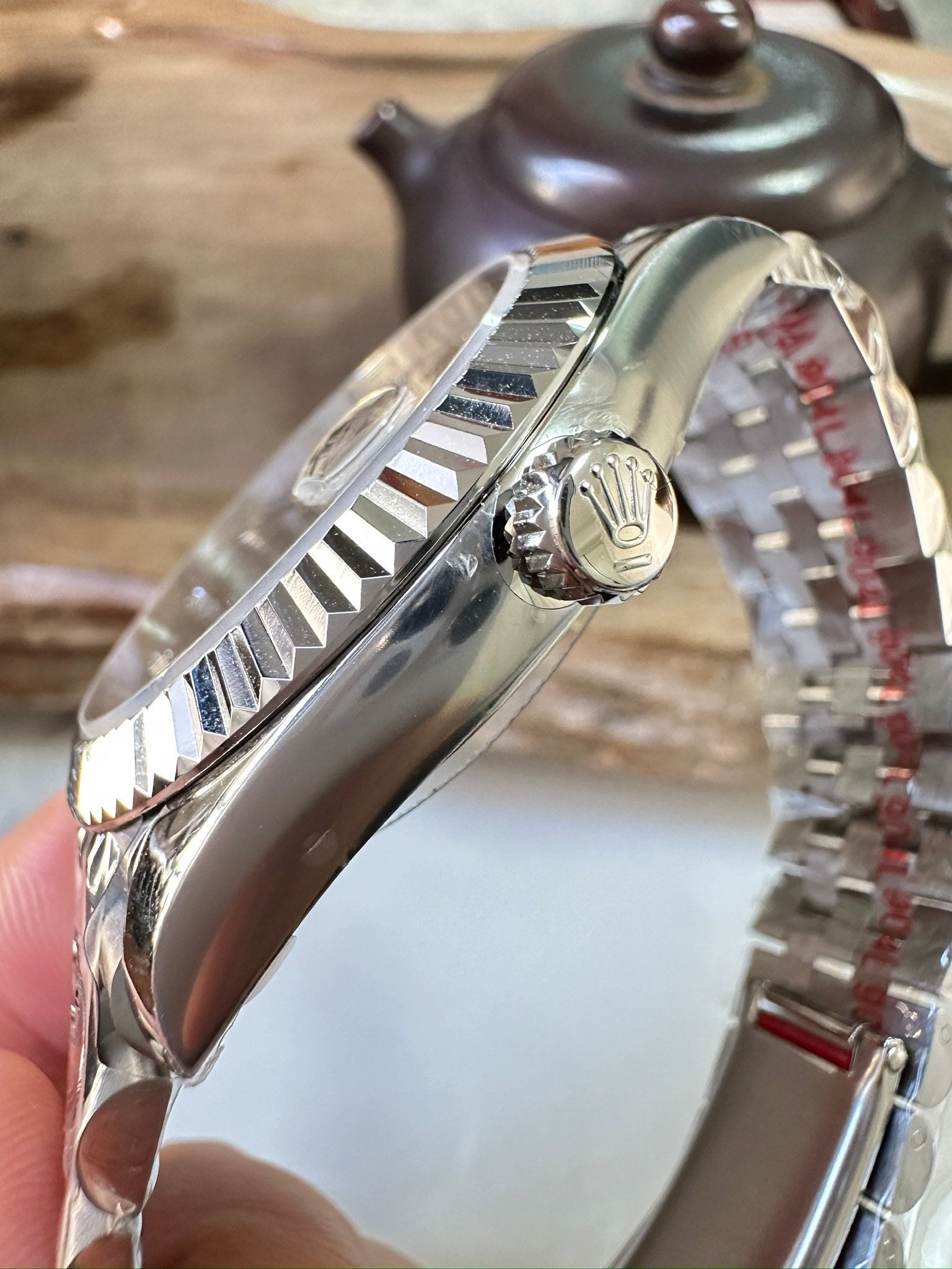 Stainless steel watch case with side crown and fluted bezel, angled view