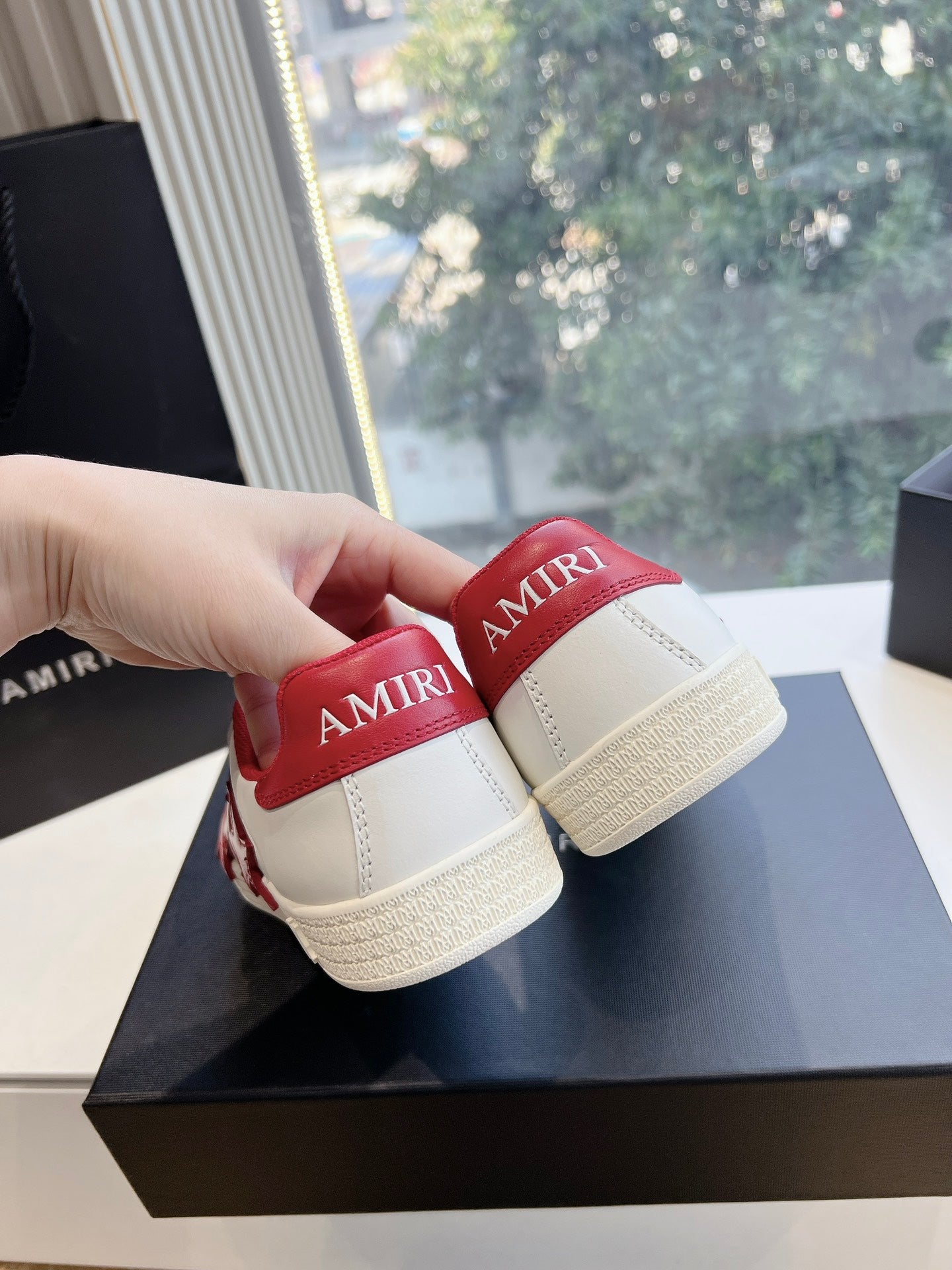 Close-up of low-top sneakers: white uppers with red heel tabs and tan soles