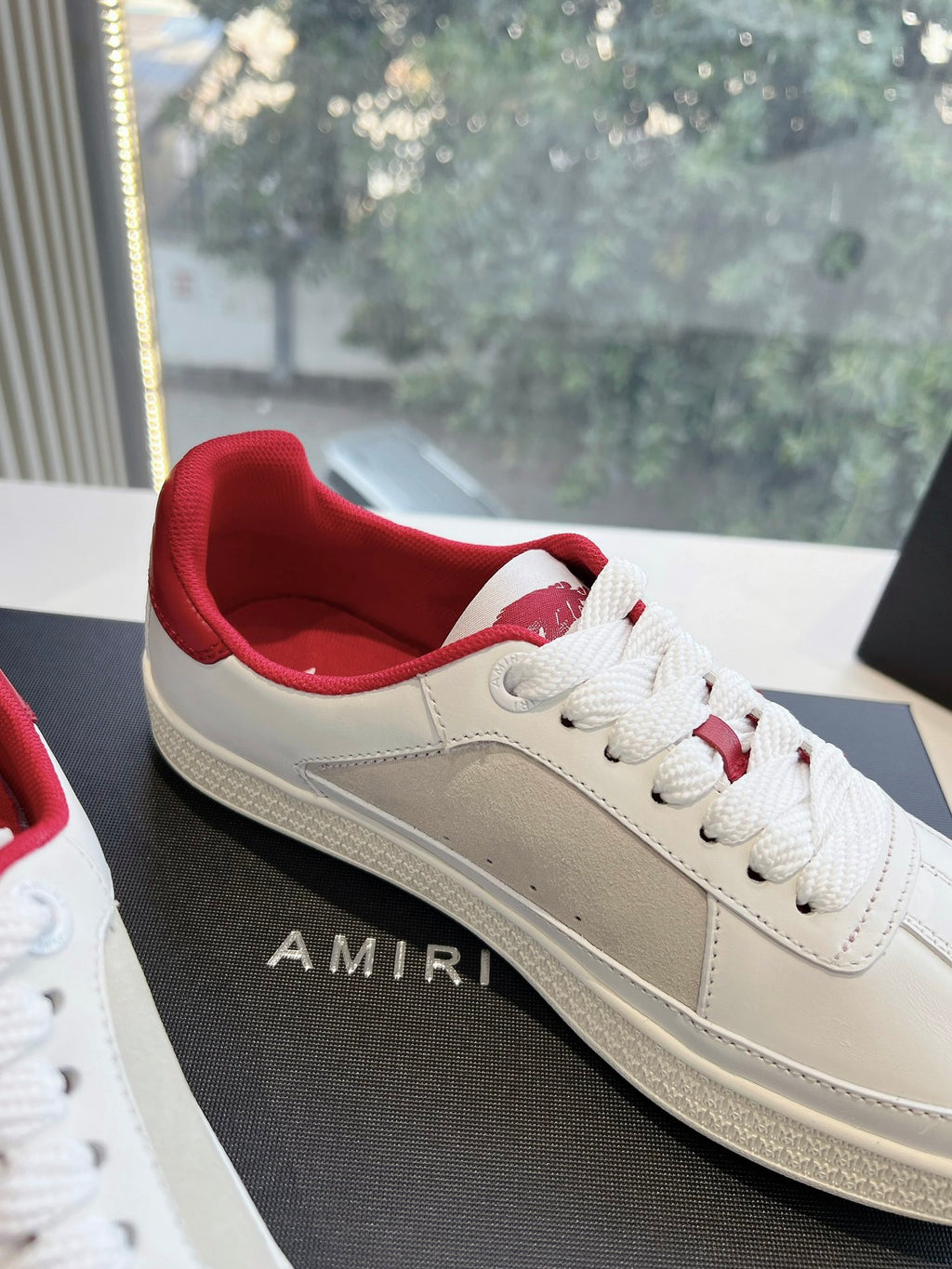 Low-top sneakers with white uppers, red collar, and lace-up front on the shoebox