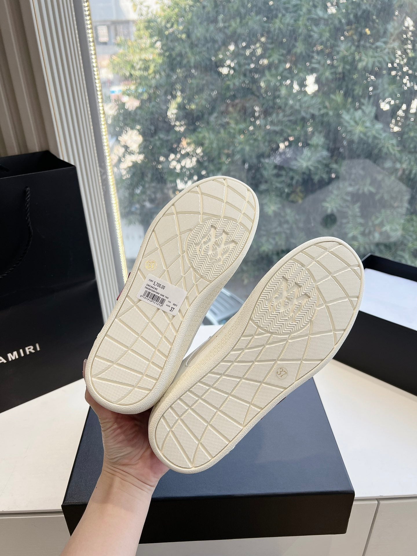 Outsoles of white low-top sneakers with grid tread and embossed logo pattern
