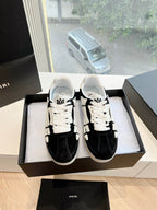 Black and white low-top sneakers, lace-up; geometric overlays; shown pair in box