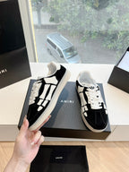 Black and white low-top sneakers, lace-up; side profile held in hand