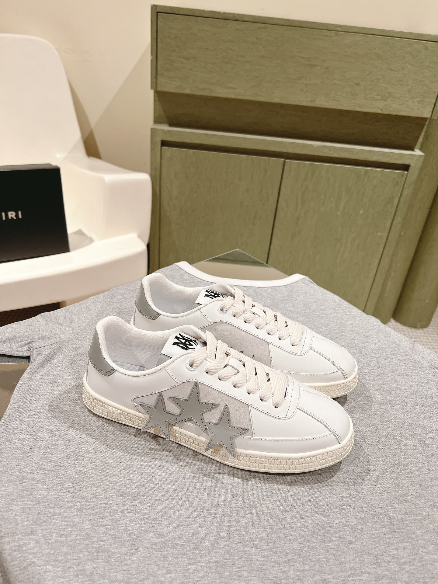 White low-top sneakers with large star panel and black logo on side, lace-up.
