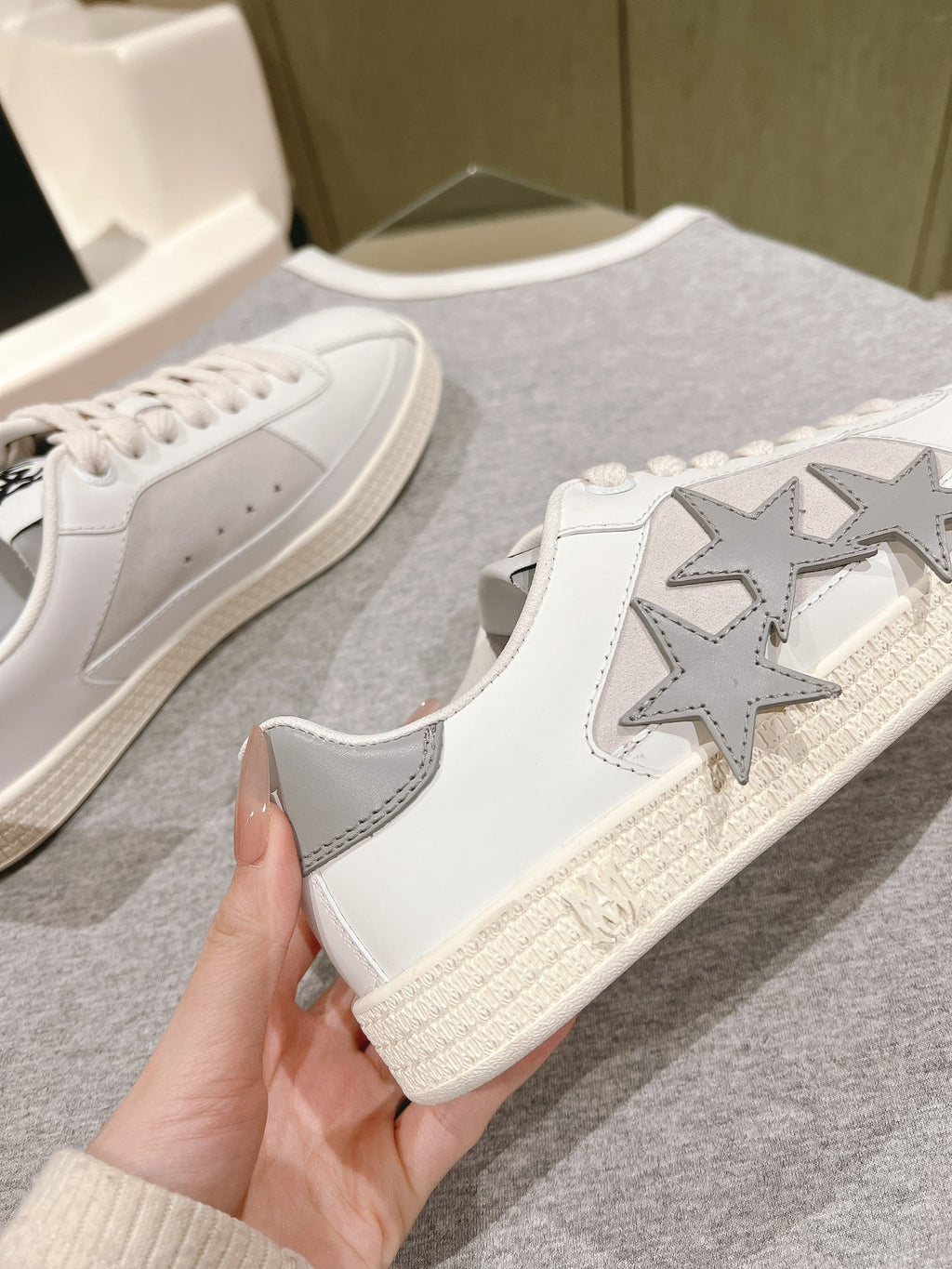 White low-top sneakers with star patch on side and textured sole, lace-up, close-up.