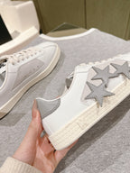 White low-top sneakers with star patch on side and textured sole, lace-up, close-up.