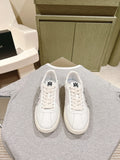 White low-top sneakers with black logo on tongue and lace-up front, side by side.