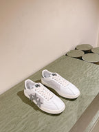 White low-top sneakers with star design on sides and black logo, laid out pair.