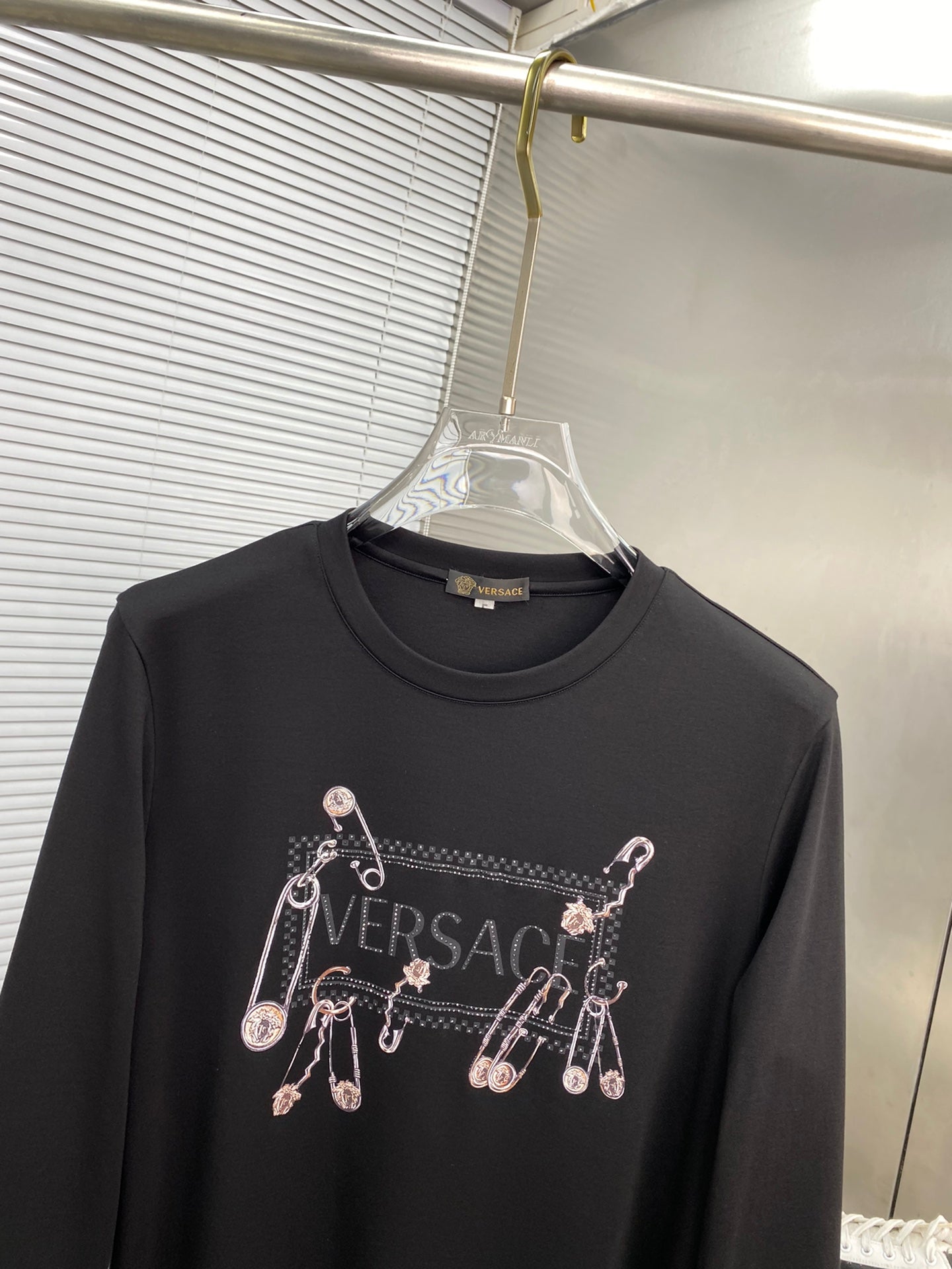 Black long-sleeve T-shirt close-up with Versace logo and charm print