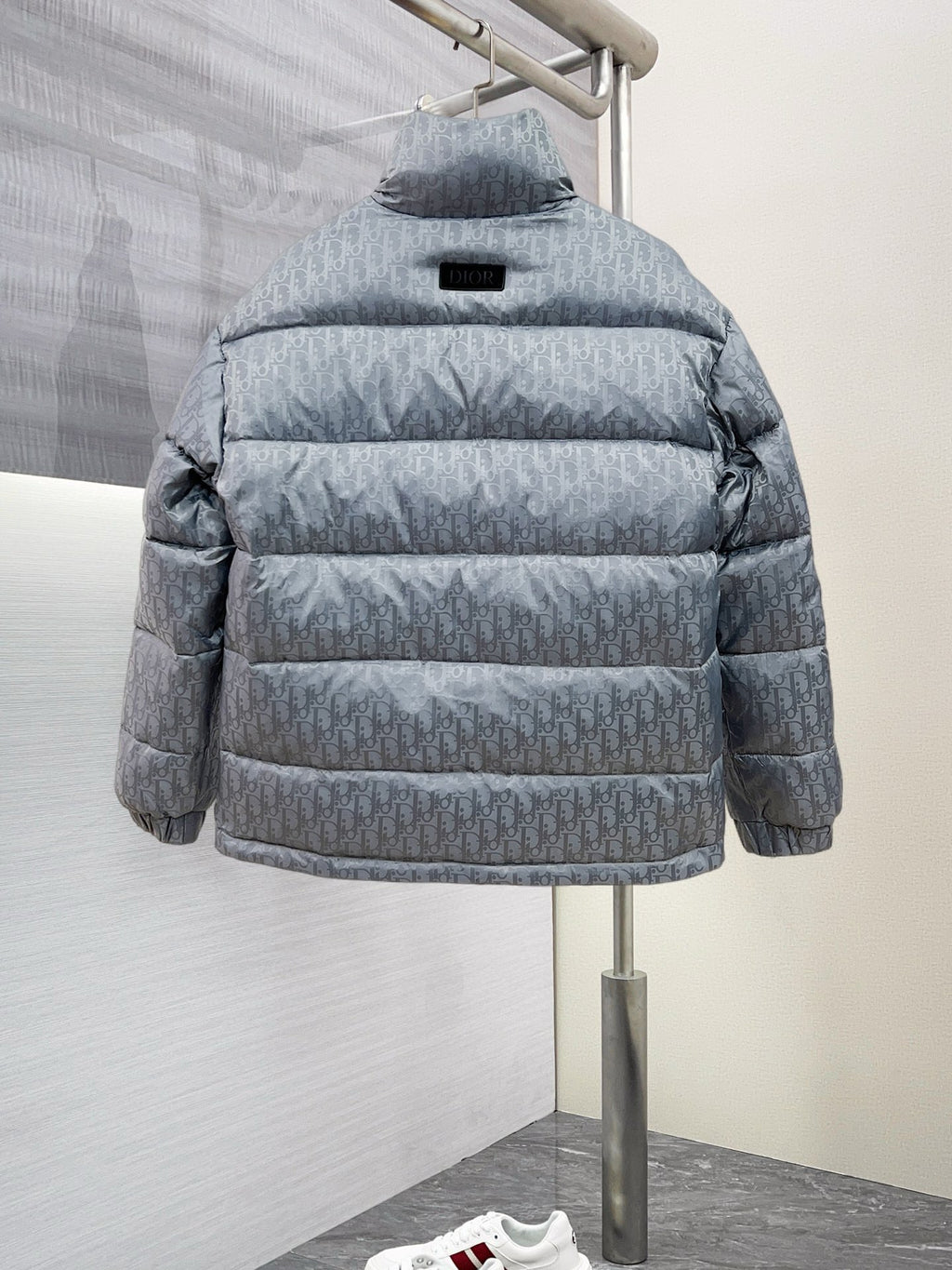 Long puffer jacket back view, light gray-blue with hood and small logo patch