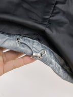 Long puffer jacket close-up of zipper pull ring on gray-blue fabric