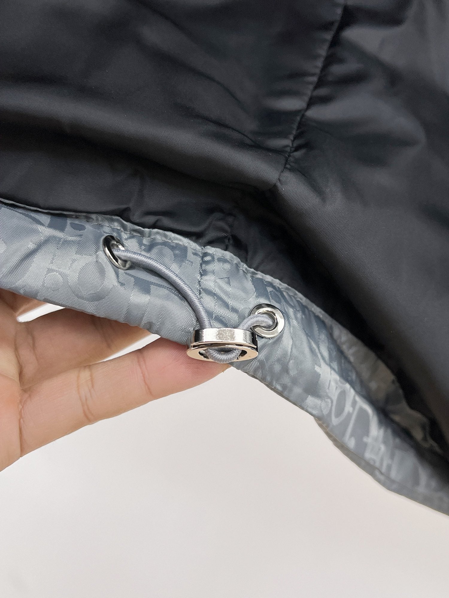 Long puffer jacket close-up of zipper pull ring on gray-blue fabric