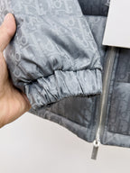 Long puffer jacket cuff close-up with elastic hem on gray-blue monogram fabric