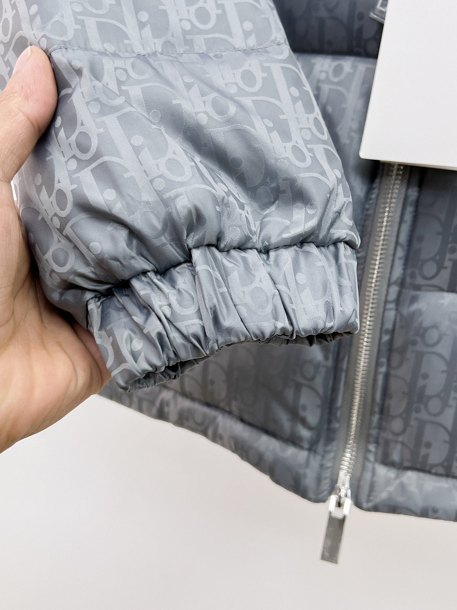 Long puffer jacket cuff close-up with elastic hem on gray-blue monogram fabric