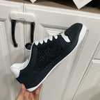 Black Gucci low-top sneaker with embossed pattern, white laces, and white midsole