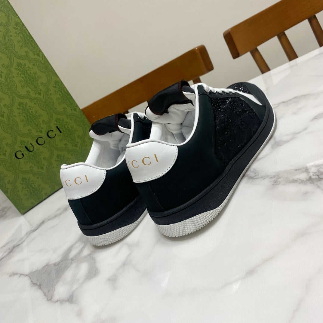 Black low-top Gucci sneakers with white laces, perforated panels, and white trim