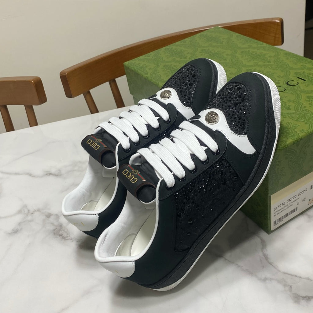 Black Gucci low-top sneakers with white laces, textured leather, and round metal eyelets
