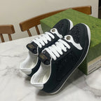 Black Gucci low-top sneakers with white laces, textured leather, and round metal eyelets