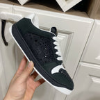 Black Gucci sneaker with perforated toe panel, white laces, and rubber sole