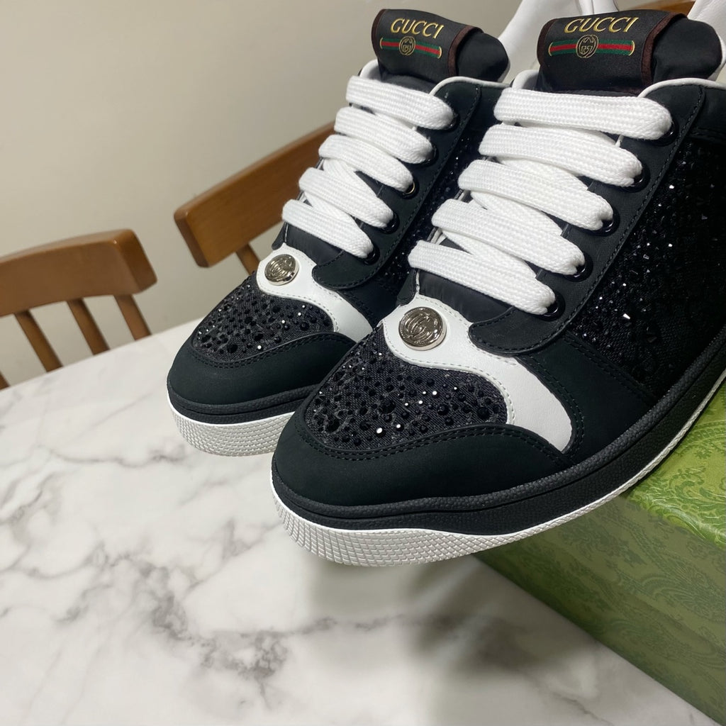 Black and white Gucci low-top sneakers with white laces and bold round metal logos