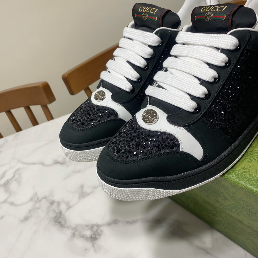 Black and white Gucci low-top sneakers with white laces and bold round metal logos