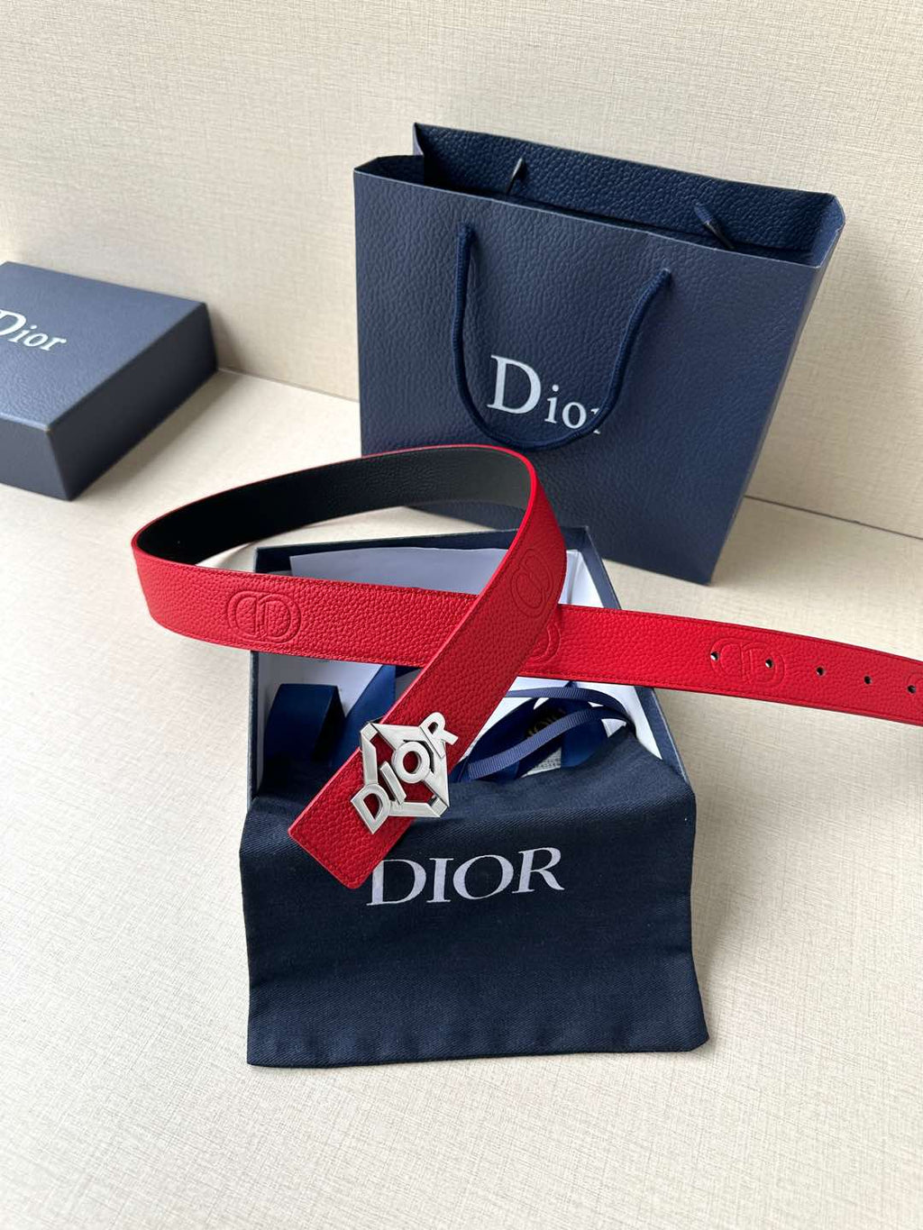 Red leather belt with silver buckle, flat lay showing embossed strap details.