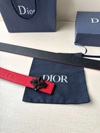 Red leather belt with black strap keeper and Dior-branded buckle on the end.