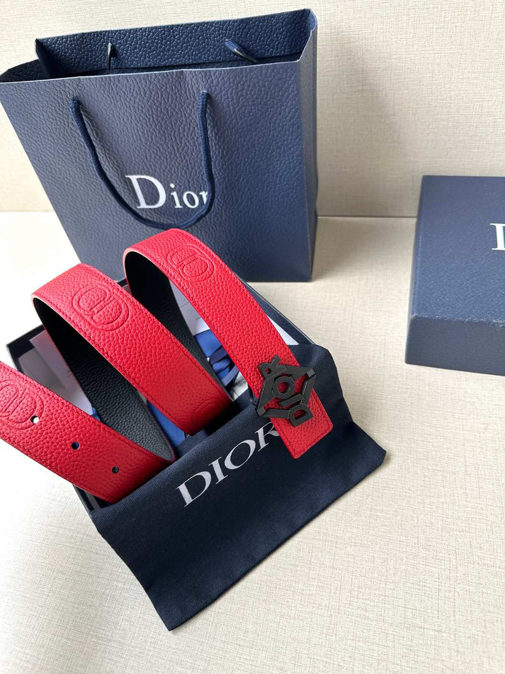 Red leather belt with silver buckle, laid with visible strap texture and hole spacing.
