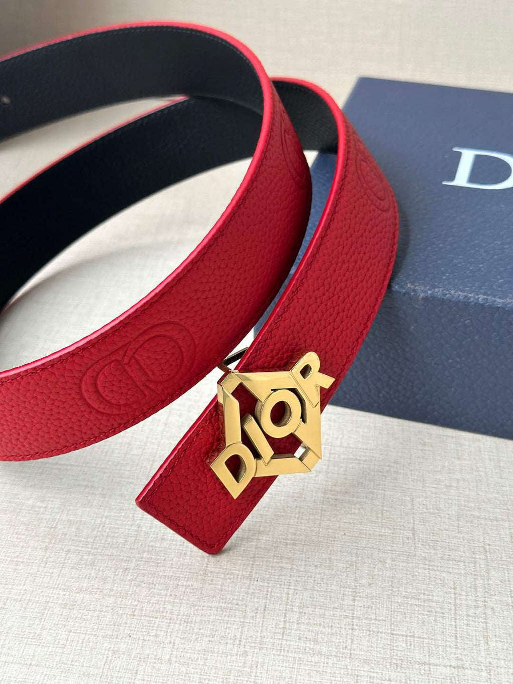 Close-up of red leather belt with silver buckle and dark inner lining at the edge.