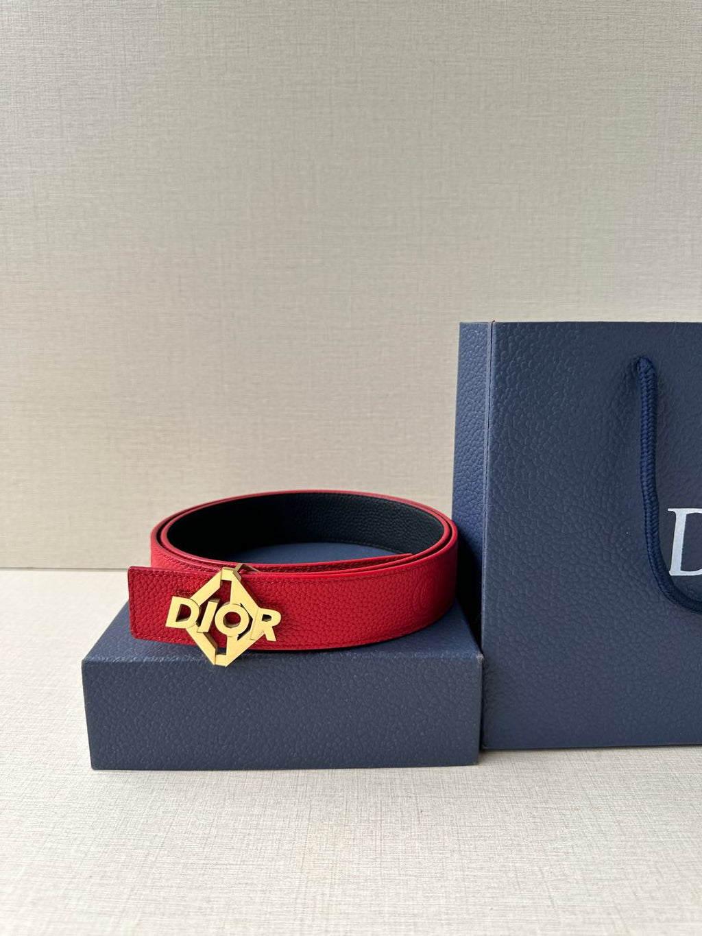 Red leather Dior belt, coiled with silver-tone buckle over an accessory box.