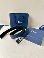Dark blue leather belt with Dior logo buckle and attached tag, on gift boxes.