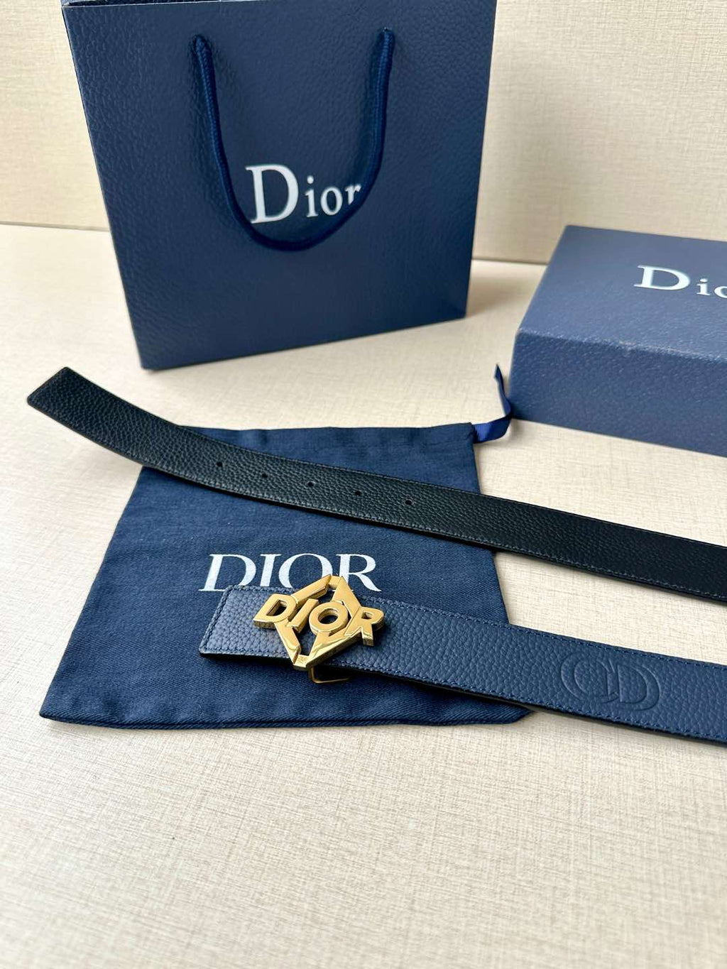 Dark blue leather belt with Dior logo buckle and matching fabric pouch and boxes.