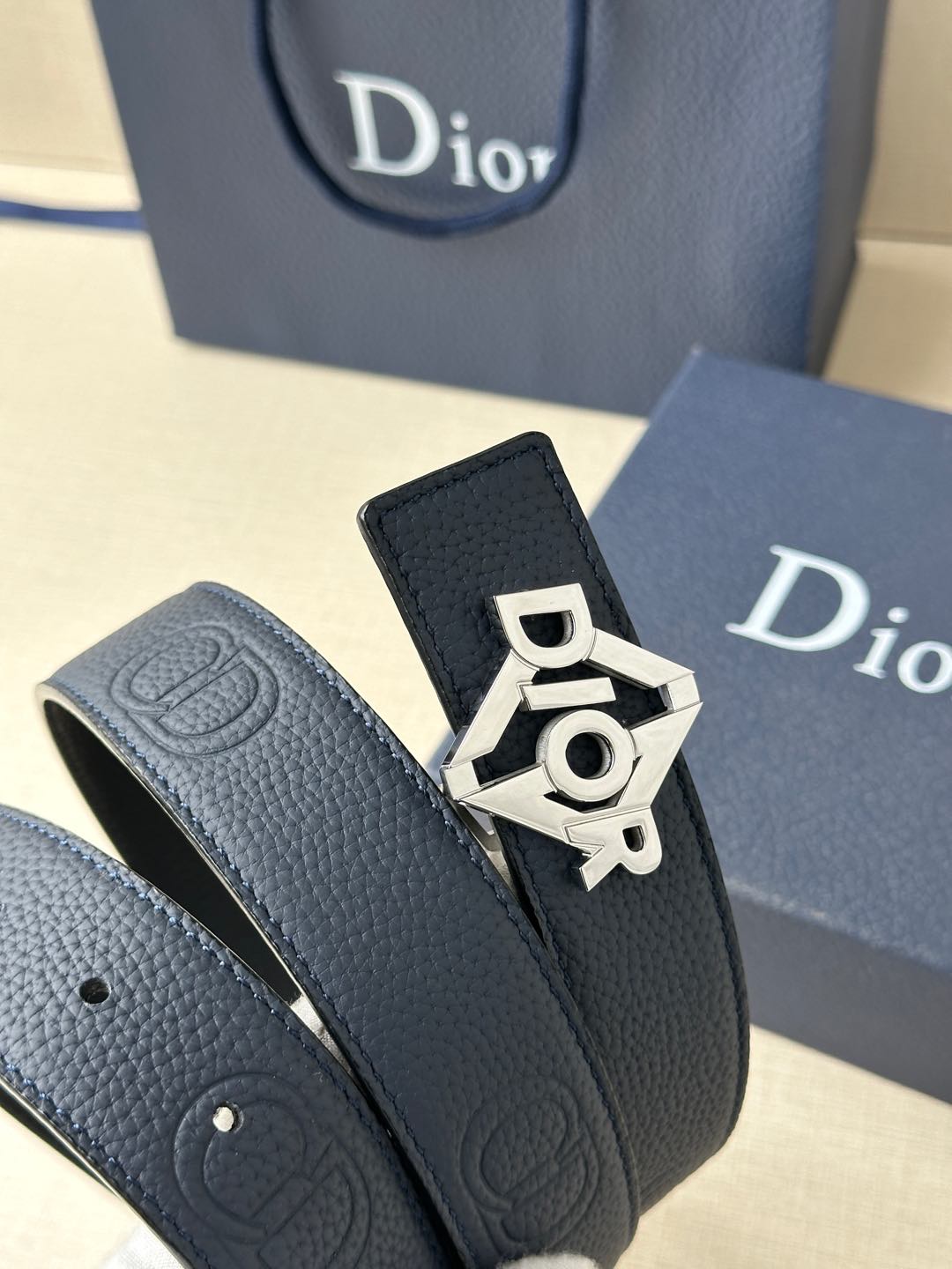 Dark blue leather belt strap with gold-toned Dior logo buckle detail.