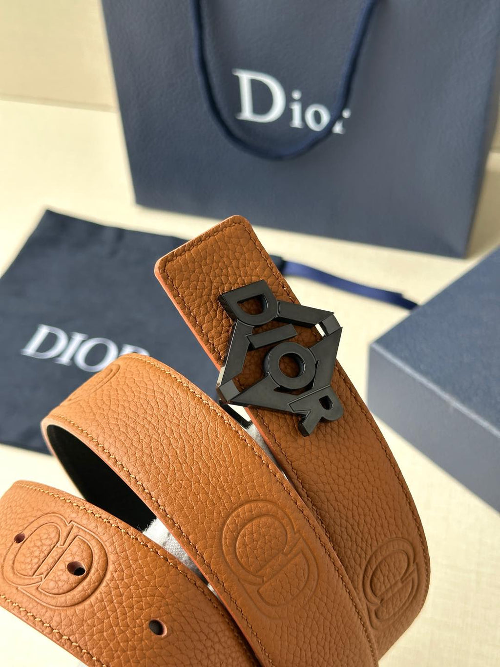 Dior belt close-up: tan leather strap with black logo buckle