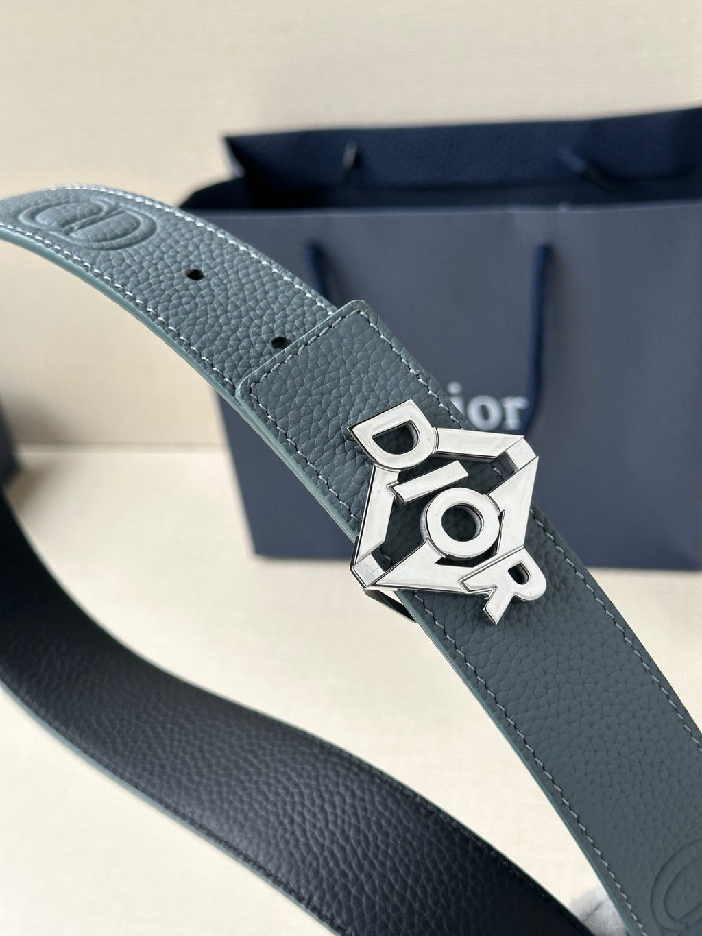 Dior belt close-up in light blue leather with silver buckle and Dior charm