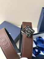 Dior belt close-up: brown leather strap with metallic Dior logo buckle.