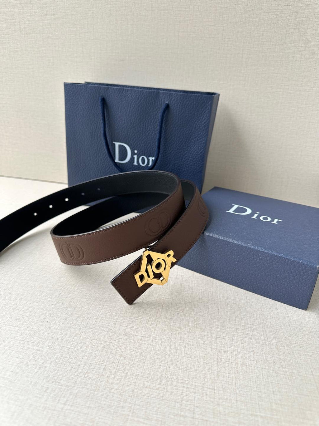 Dior belt on display: dark brown leather strap with gold-tone Dior buckle.