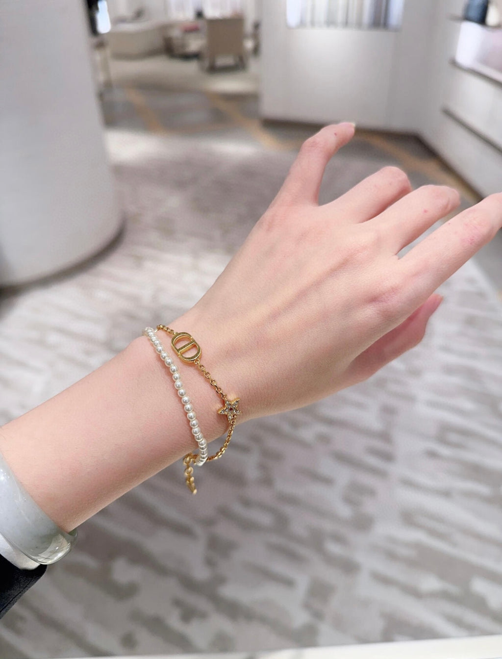 Pearl and gold charm bracelet on wrist with oval link and small pendant