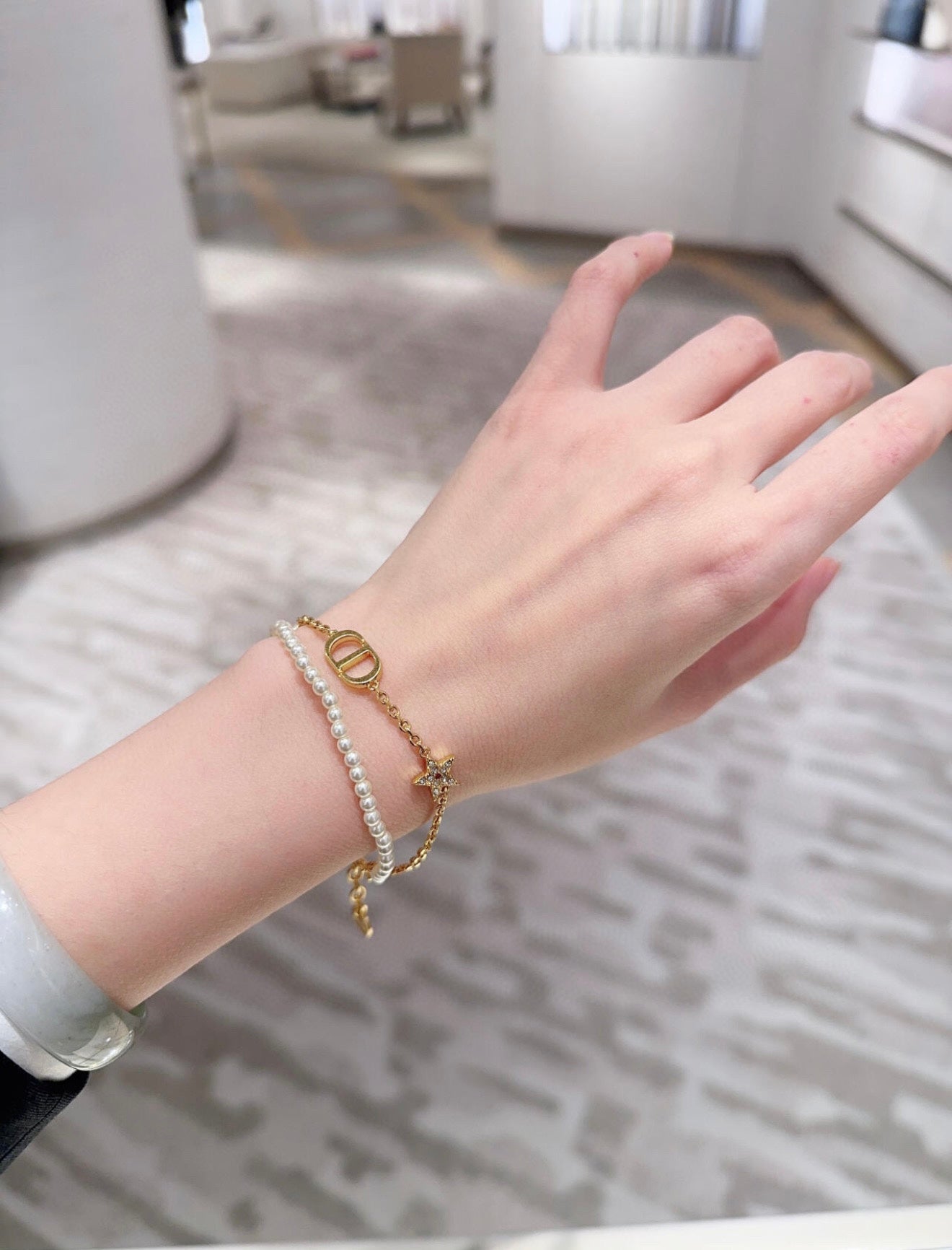 Pearl and gold charm bracelet on wrist with oval link and small pendant