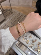 Pearl and gold charm bracelet on wrist with oval DIOR link and star charm
