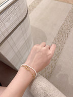 Pearl and gold charm bracelet on wrist with DIOR pendant and clasp