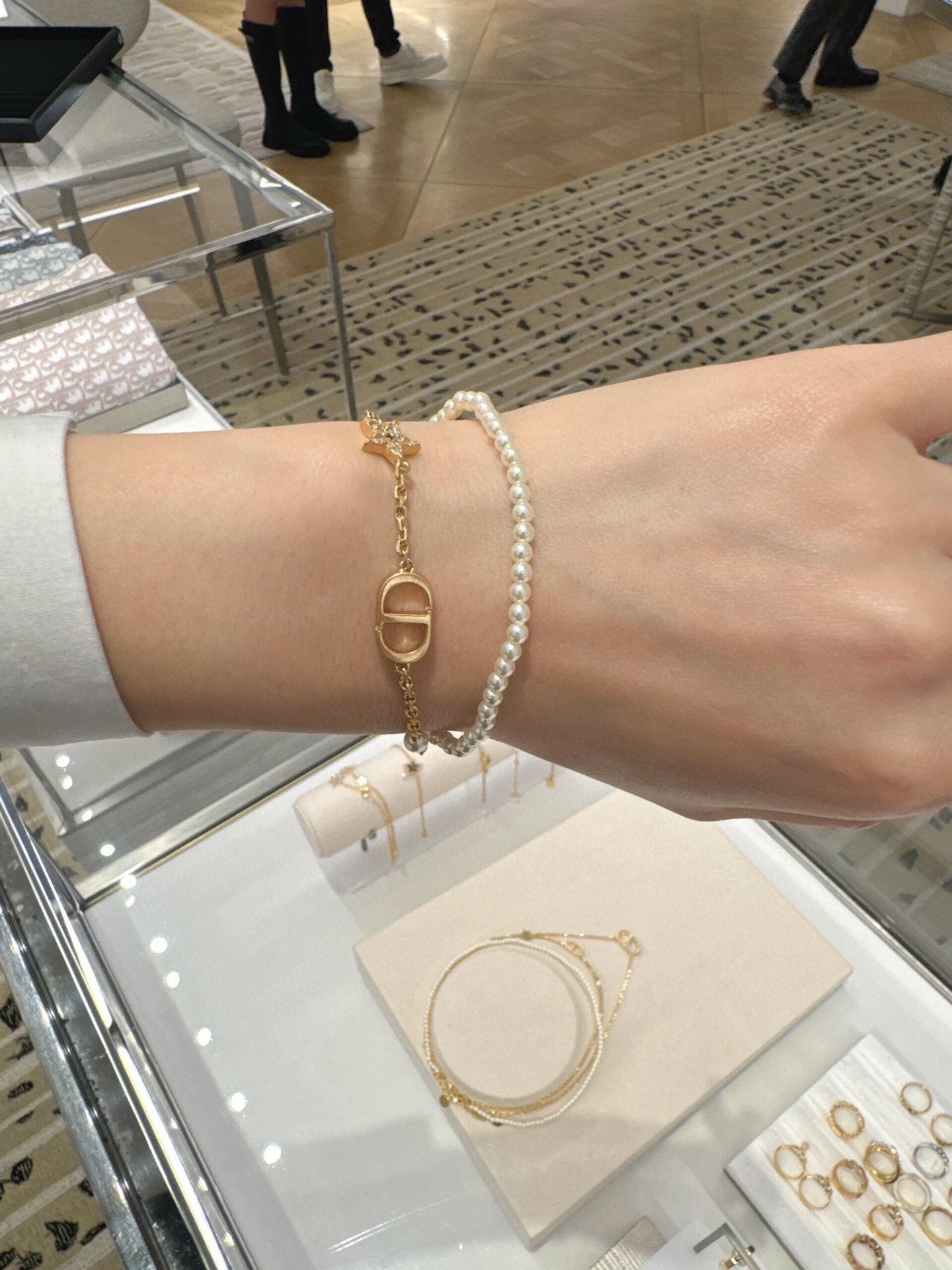 Pearl and gold charm bracelet on arm with oval gold link and dangling detail