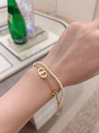 Pearl and gold bracelet on wrist with DIOR D pendant and star charm
