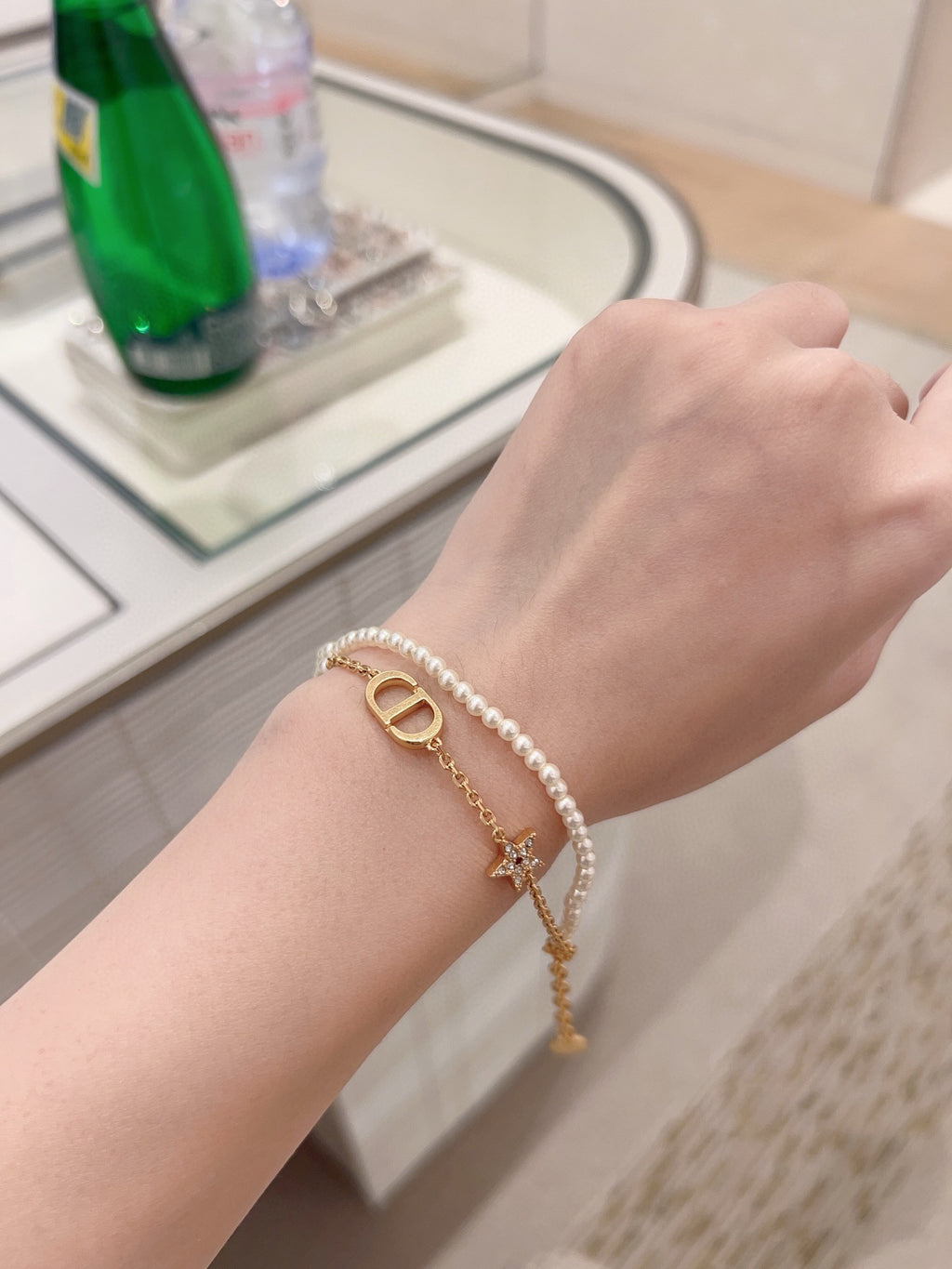 Pearl and gold charm bracelet on wrist with gold D pendant and dangling star