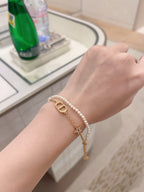 Pearl and gold charm bracelet on wrist with gold D pendant and dangling star
