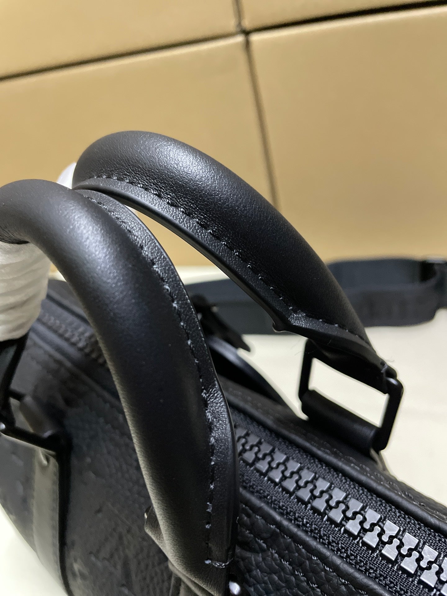 Monogram duffel strap close-up with patterned stitching and dark leather edges