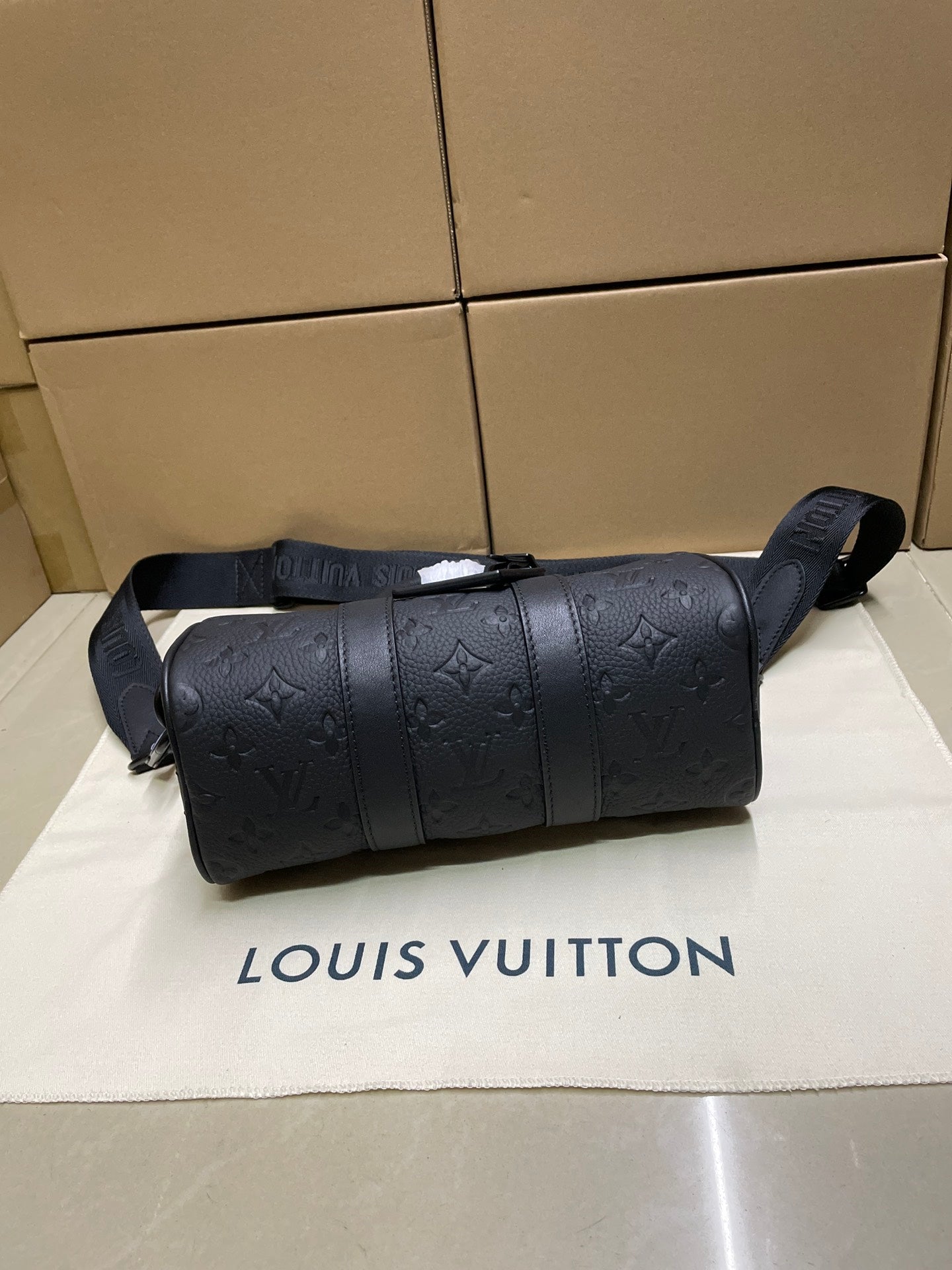 Monogram duffel bag front view with rounded top and shoulder strap, dark leather