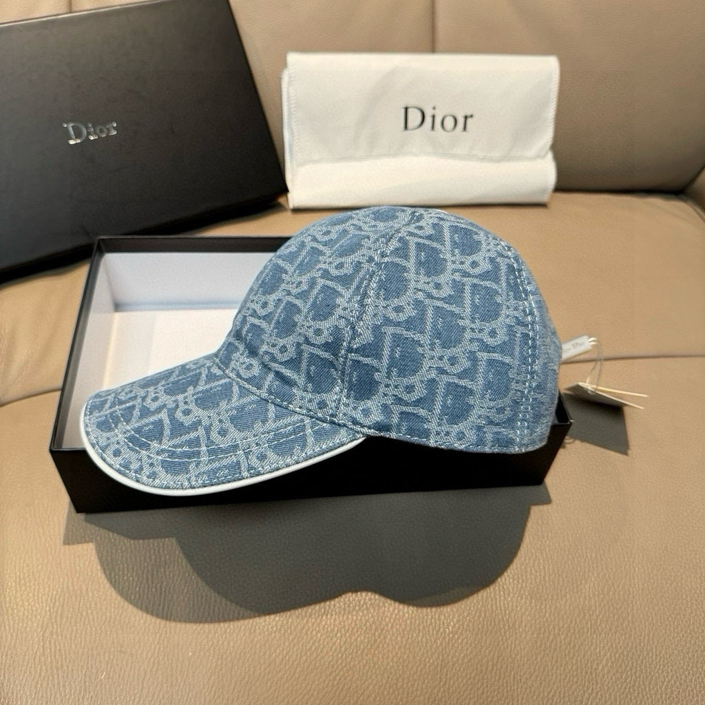 Dior cap in blue monogram denim with curved brim, resting on box