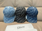 Three Dior logo-print caps: two dark blue and one black, side-by-side on a couch.